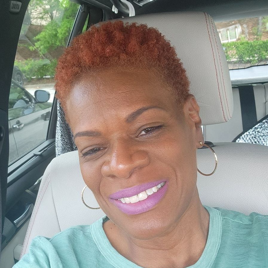 A woman is smiling while sitting in the back seat of a car.