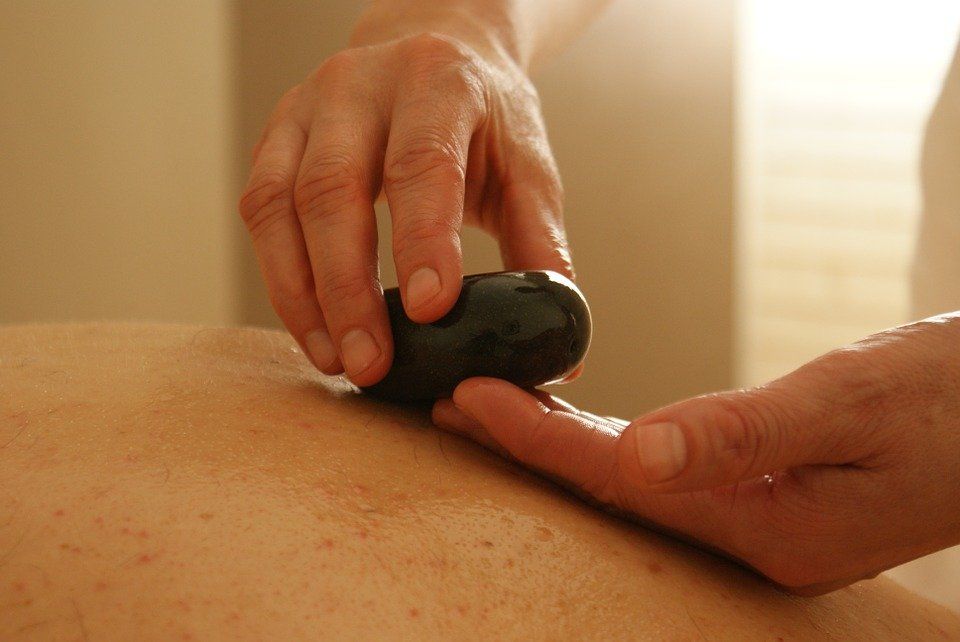 A person is getting a massage with a rock on their back.