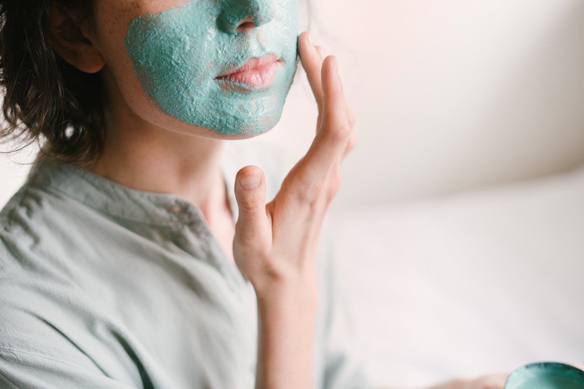 A woman is applying a blue mask to her face.
