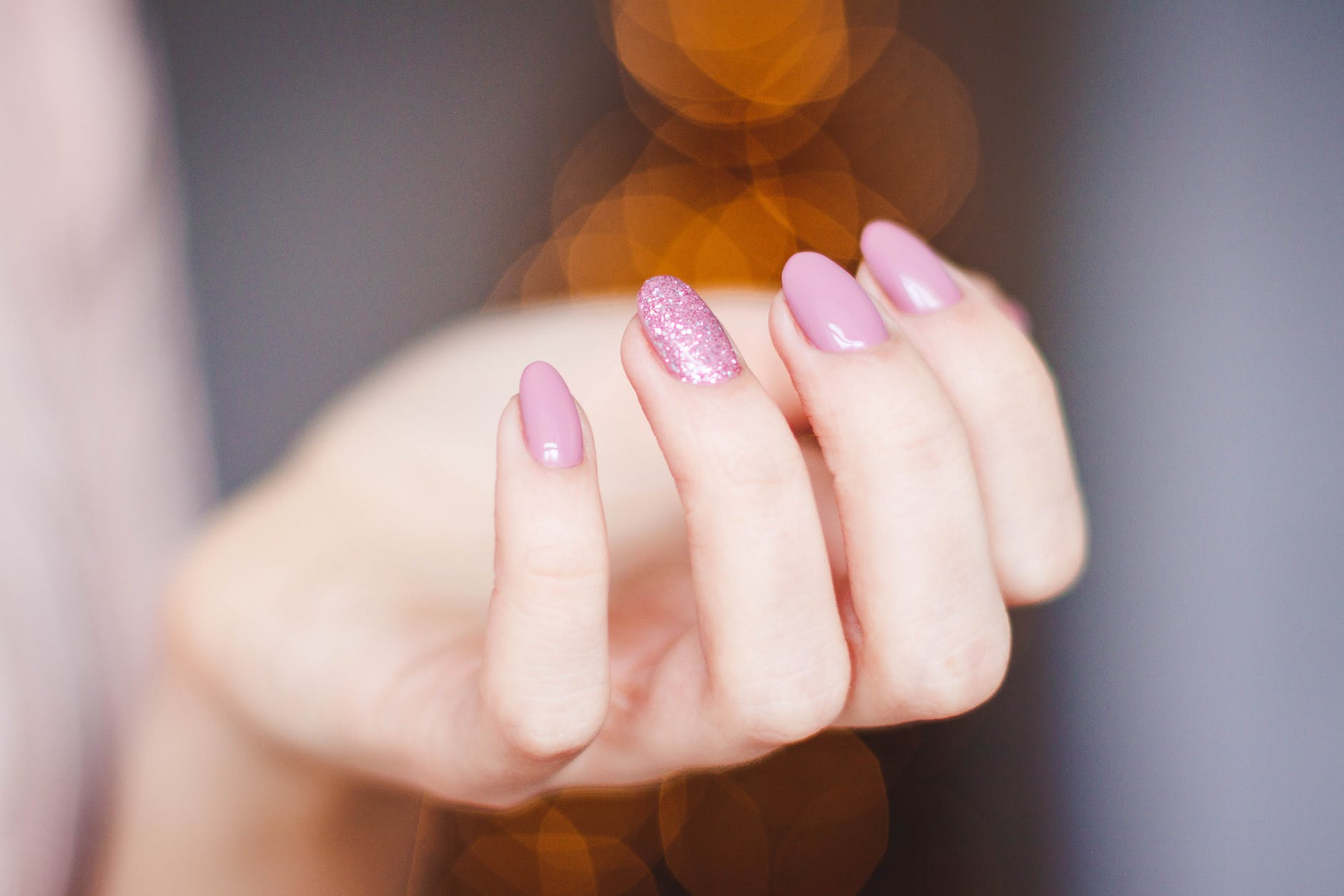 A close up of a woman 's hand with pink nails.