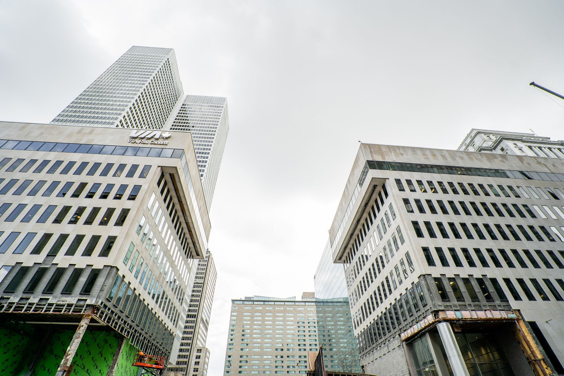 Low-angle view of modern skyscrapers against a cloudy sky. Gray concrete buildings with window patterns.