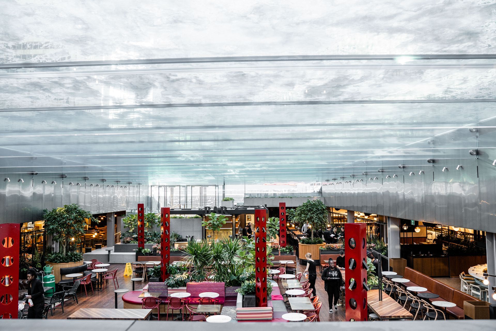 Construction site with workers in safety vests, crane, and modern buildings in background.