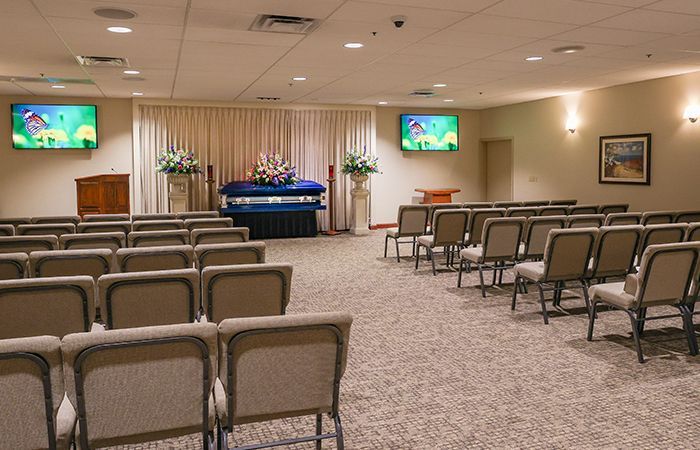 a funeral home with rows of green chairs and a television on the wall .