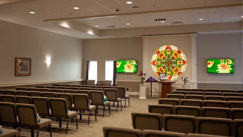 an empty auditorium with rows of seats and a coffin in the background .