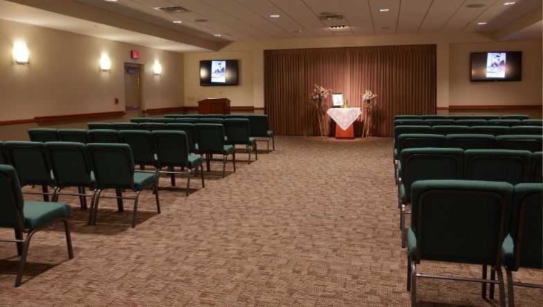 a funeral home with a coffin and two televisions on the wall .