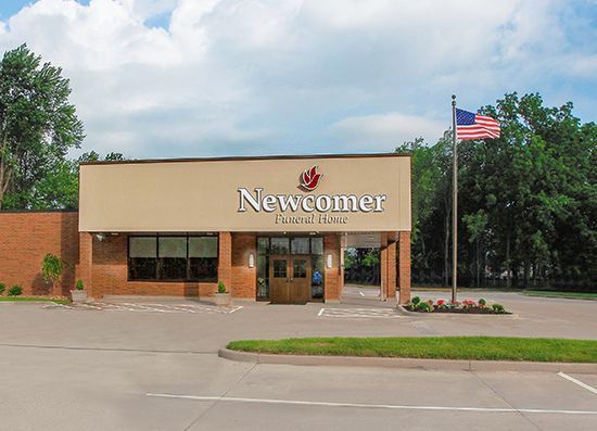 A large white building with a brick facade and a parking lot in front of it