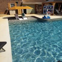 Pool with clear water, lounge chairs, and a basketball hoop. Sunny outdoor setting.