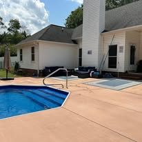 Pool, house, patio. Blue water, white house with dark trim, sunny day.