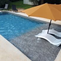 Swimming pool with blue water, tan umbrella, and white chaise lounge.