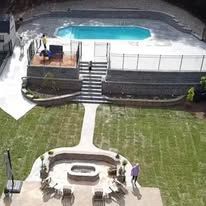 Aerial view of a swimming pool with a surrounding patio and landscaping.