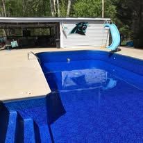 Blue tiled swimming pool with slide, and Panthers logo on a nearby building.