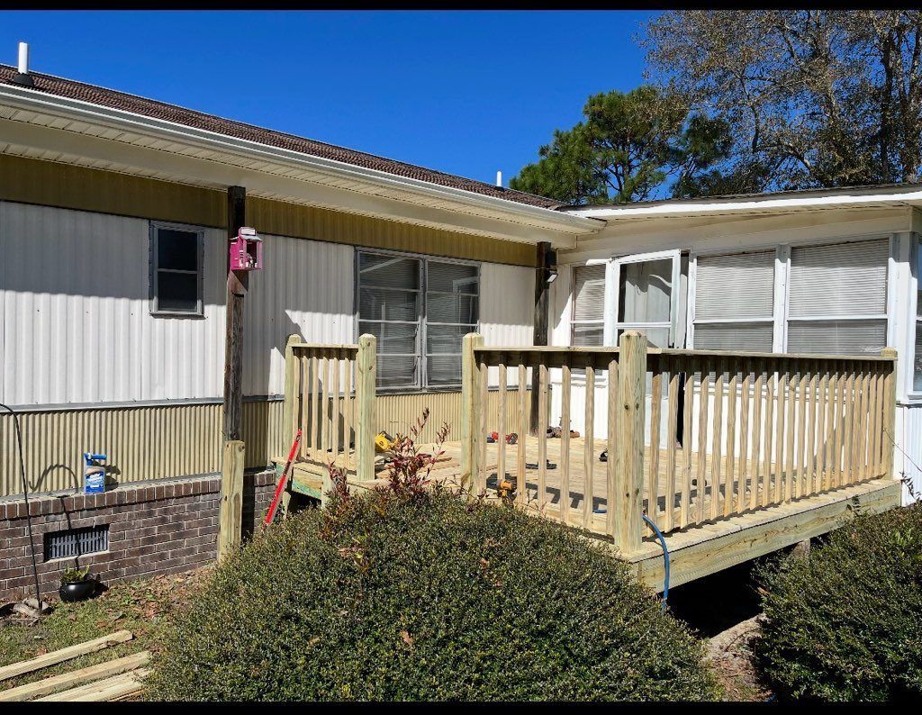 A newly built wooden deck attached to a house with white siding and a blue sky.