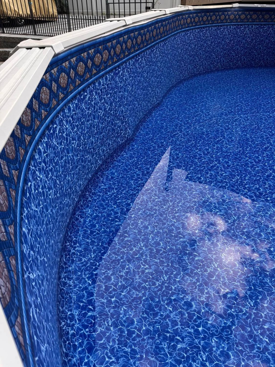 Blue-patterned swimming pool interior with some water filled. White border at the top edge.