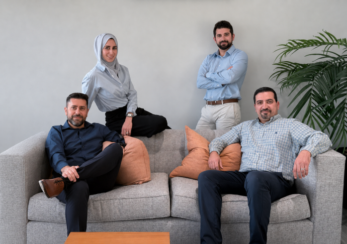 Smiling family of four leaning over a couch in a bright living room