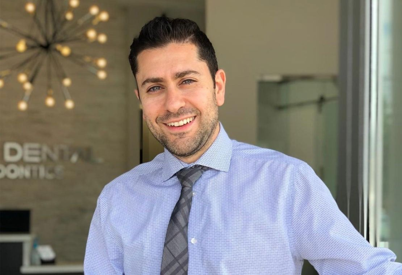 Smiling man in a light blue shirt and tie standing in a modern office entrance