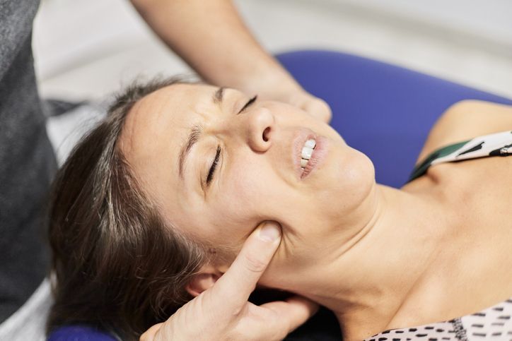Woman receiving a neck massage while lying on a blue cushion