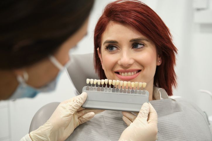 Dentist showing a woman a set of teeth models while she smiles in a clinic