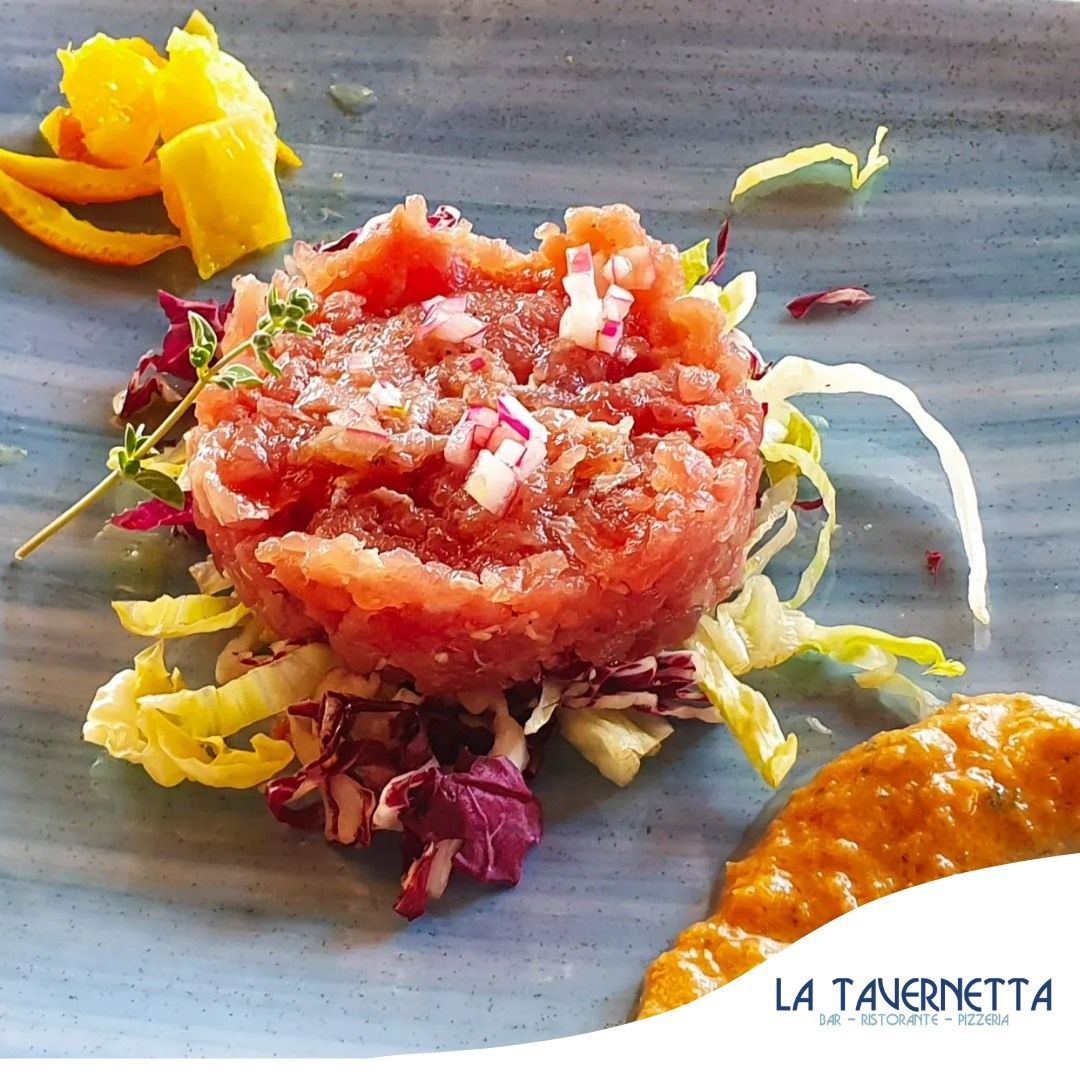 Un piatto con tartare di tonno, verdure, scorza d'arancia e salsa.