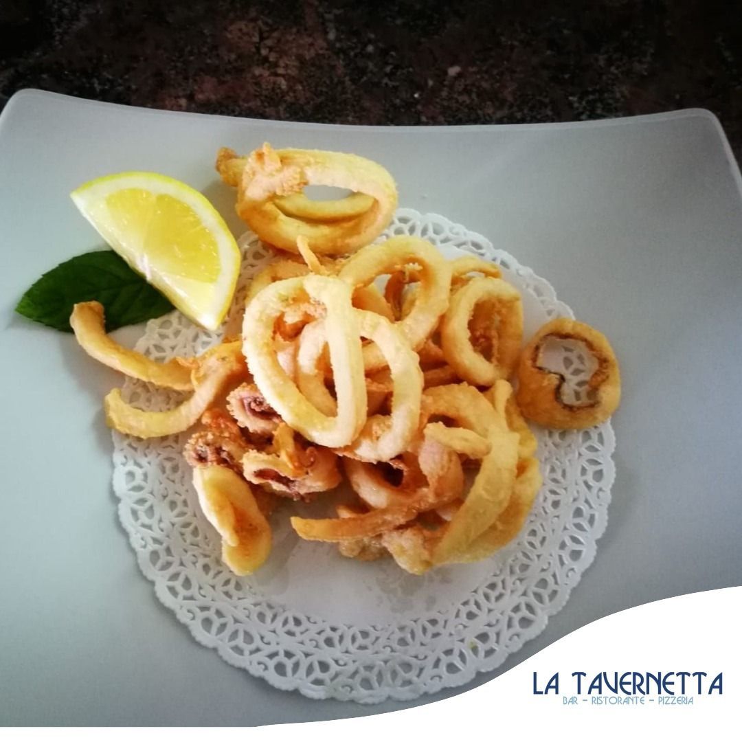 Calamari fritti con fetta di limone su un piatto bianco.