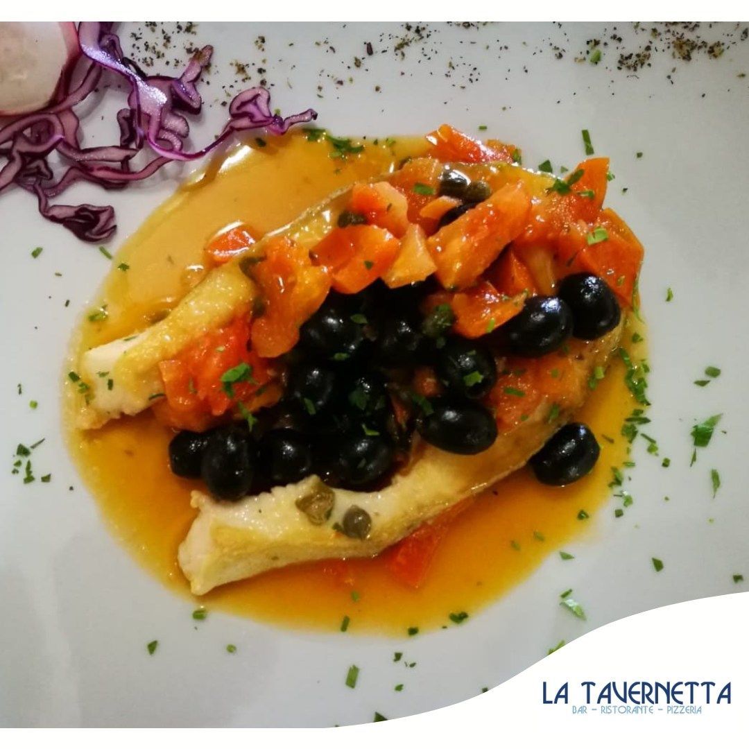 Piatto di pesce con olive, pomodori e capperi su un piatto bianco.