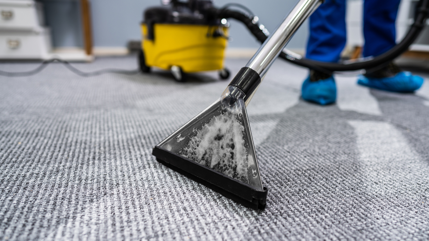 Carpet being cleaned with a yellow vacuum cleaner.