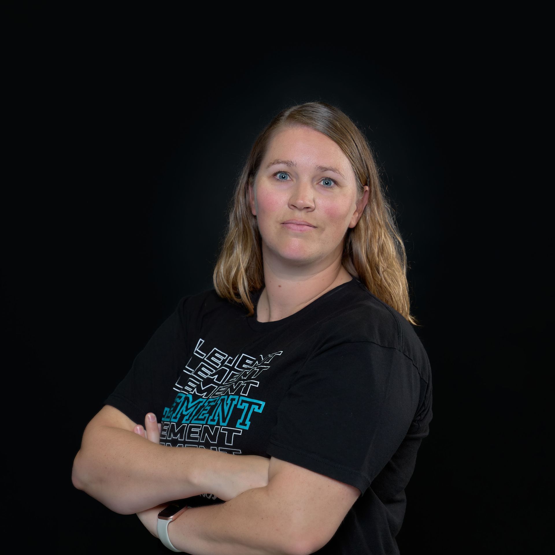 A woman in a black shirt is standing with her arms crossed.
