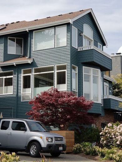A silver car is parked in front of a blue house