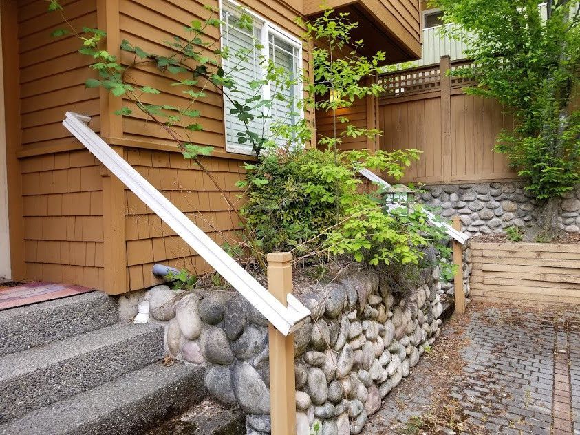 A house with stairs and a stone wall in front of it