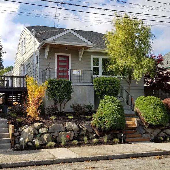 A gray house with a red door and stairs