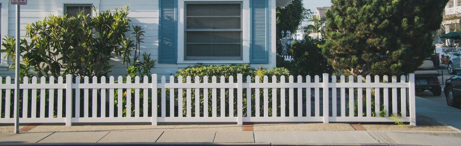 A white picket fence on the street of a Sarosota home.