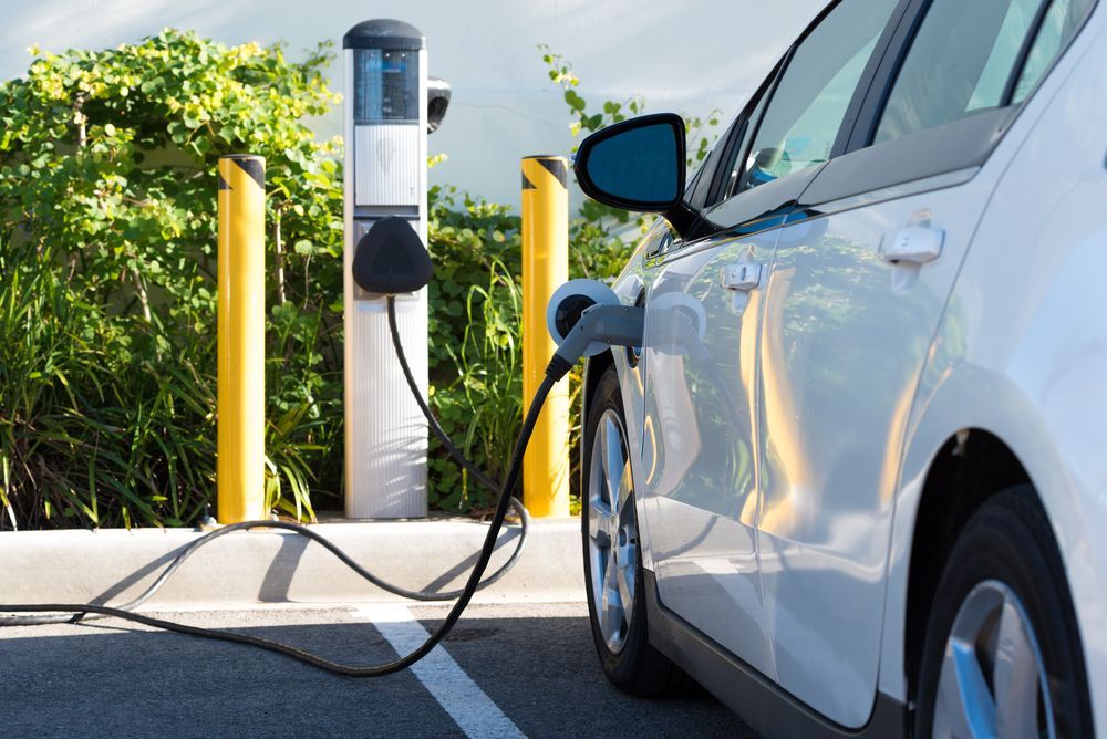 A White Electric Car Parked at A Charging Station — John McEwan Electrical In Dapto, NSW