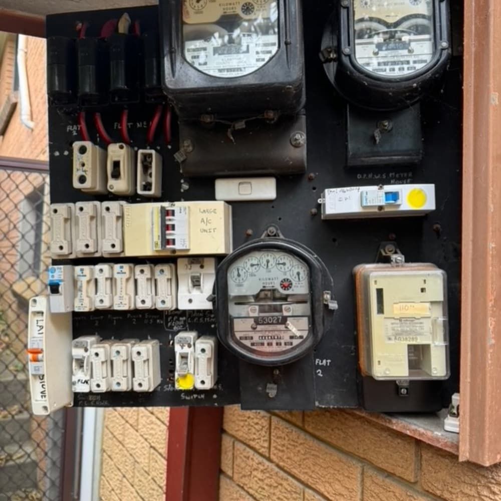 Electrical Panel on a Brick Wall With Multiple Meters, Switches, and Fuses