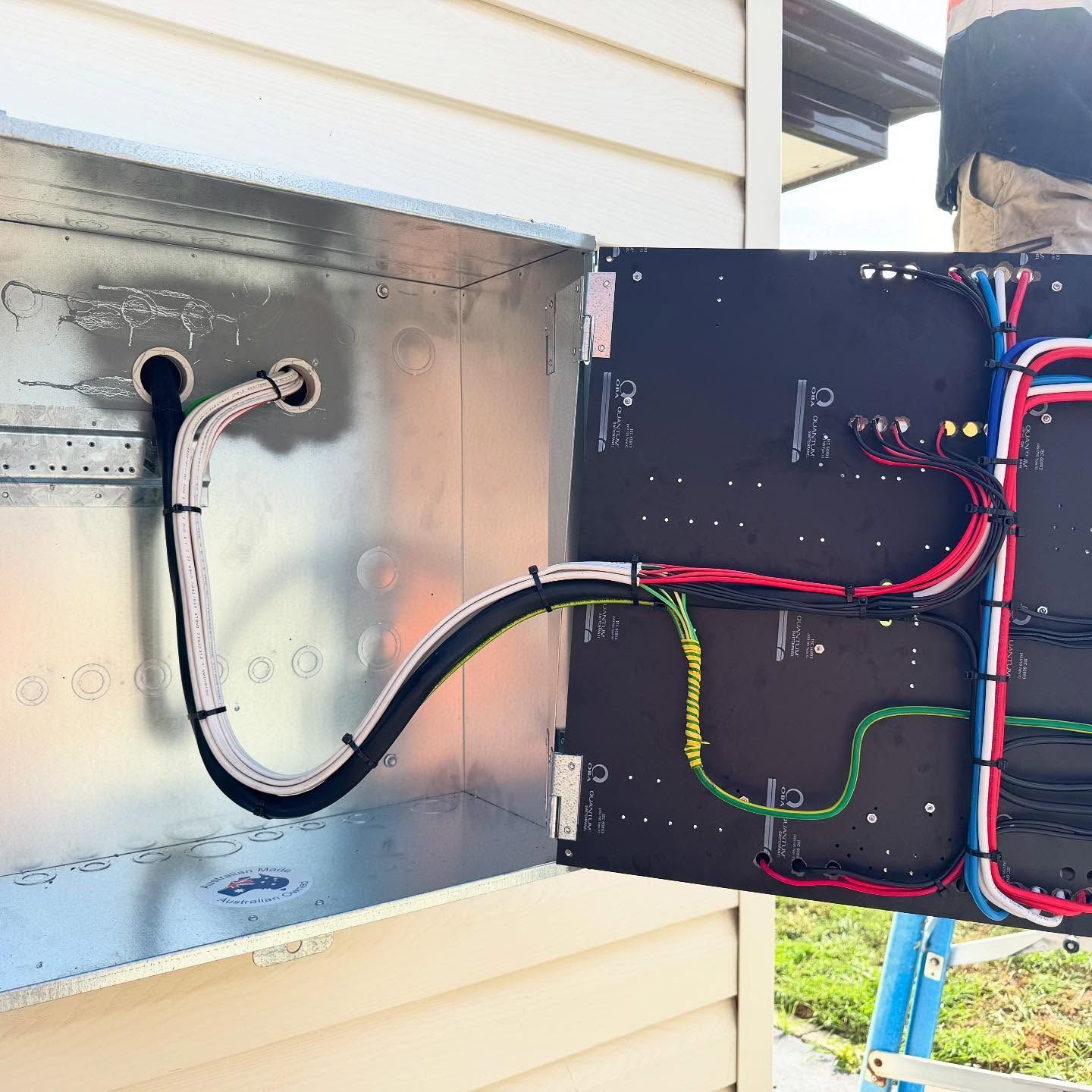 Electrical panel with wires being installed outside on a building.