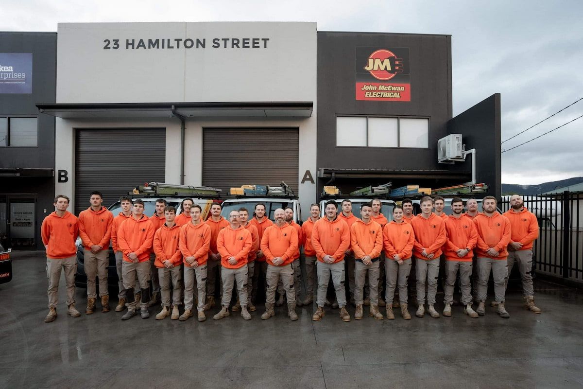 A Group of Men Are Posing for a Picture in Front of a Building — John McEwan Electrical in Dapto, NSW