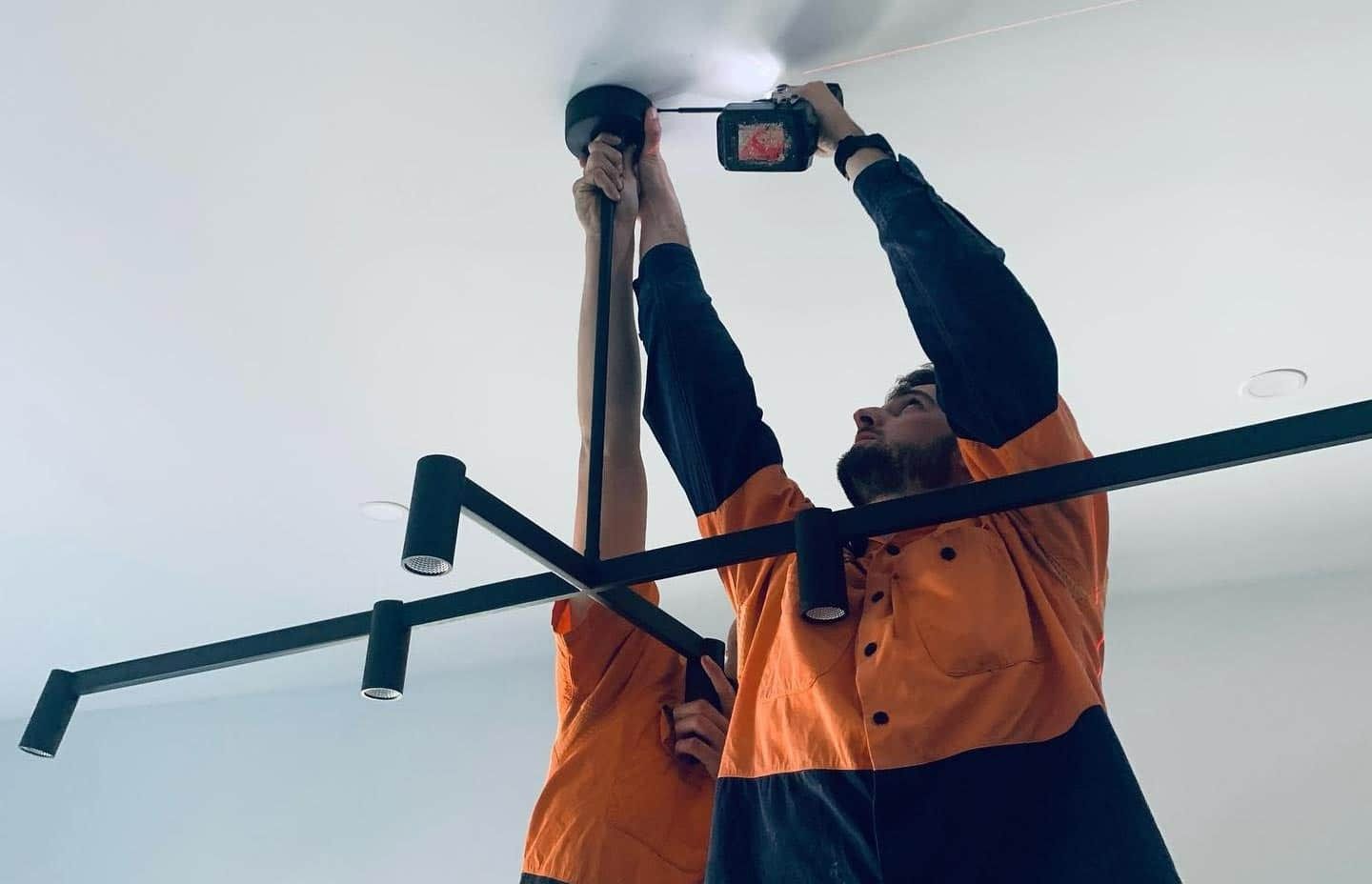Two Men Are Working On A Ceiling With A Drill — John McEwan Electrical In Kiama, NSW