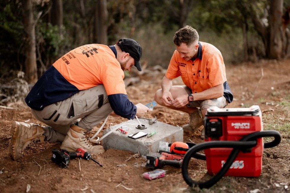 Two Men Are Working on a Piece of Equipment in the Woods — John McEwan Electrical in Dapto, NSW