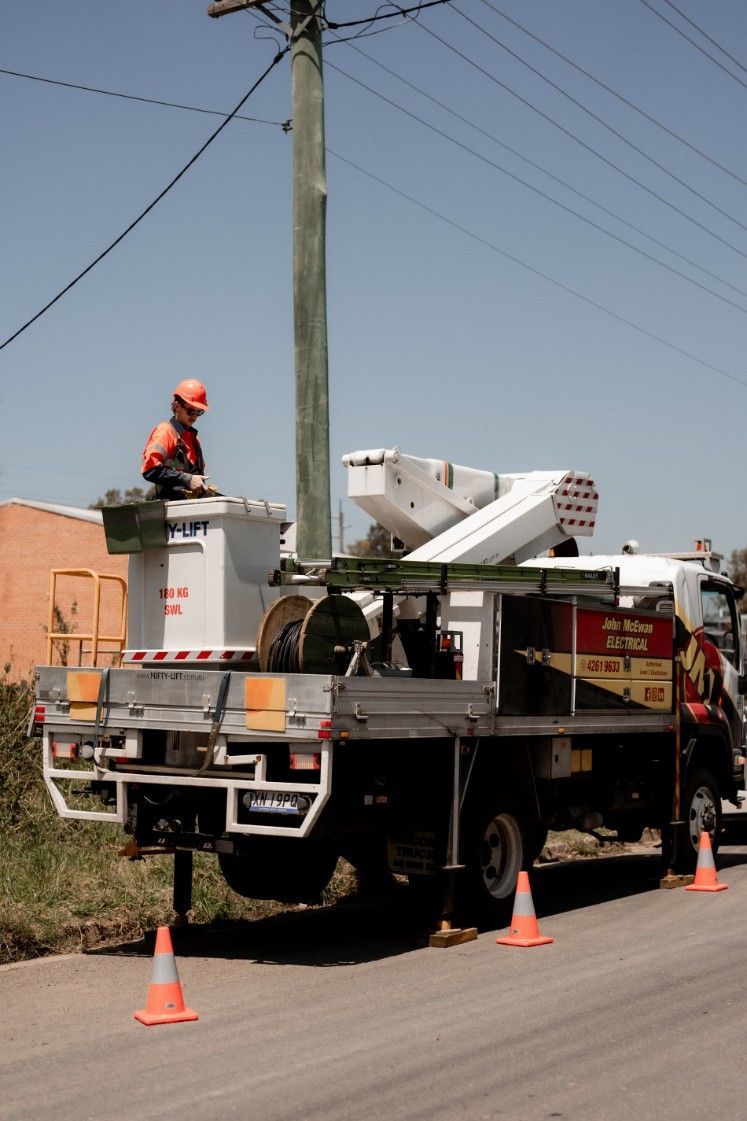 A Man is Sitting on Top of a Utility Truck — John McEwan Electrical In Dapto, NSW