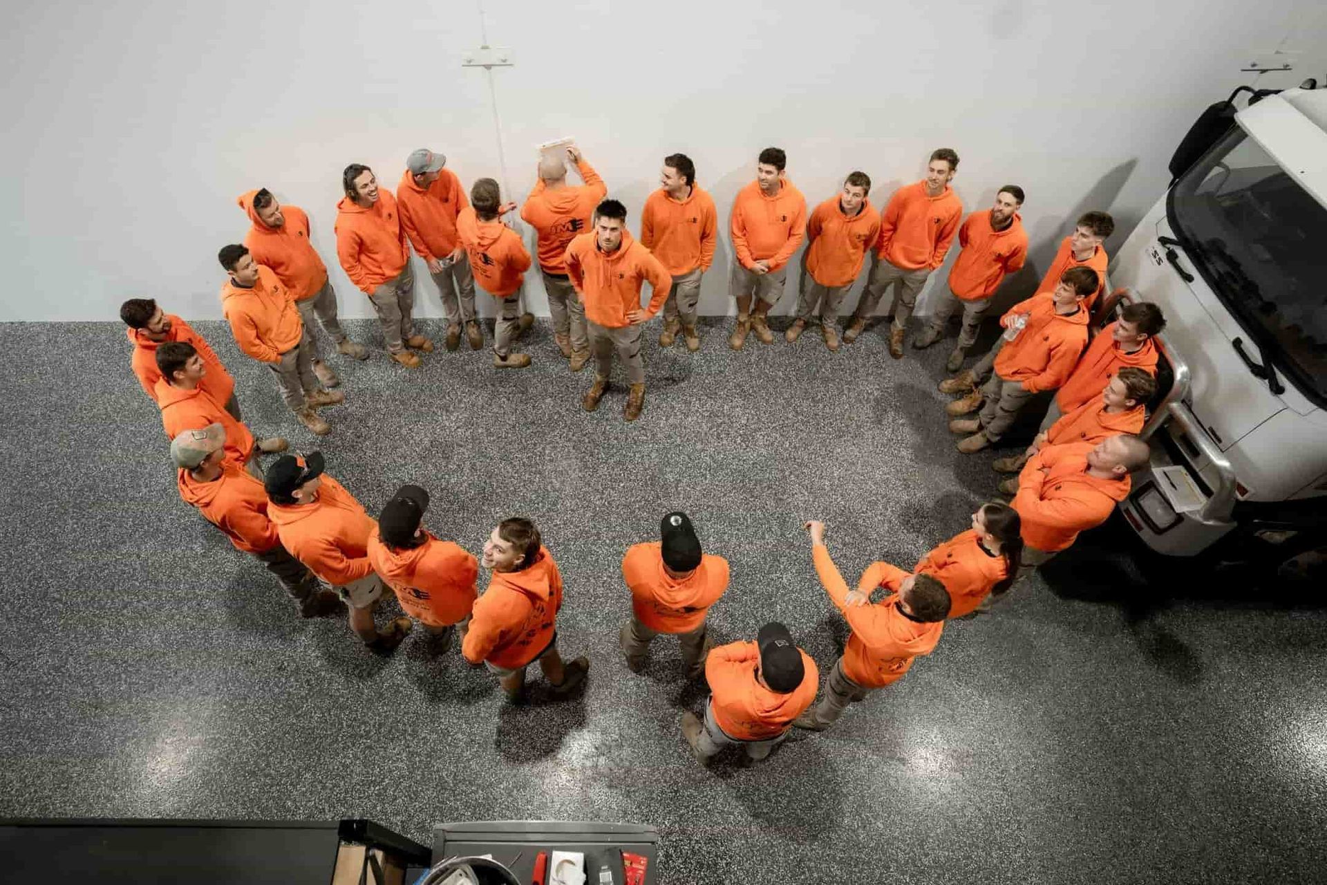 A Group of People Are Standing in a Circle in Front of a Truck — John McEwan Electrical in Woonona, NSW