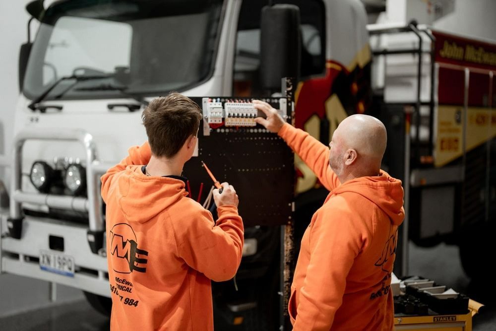 Two Men Are Working On A Truck In A Garage — John McEwan Electrical In Dapto, NSW