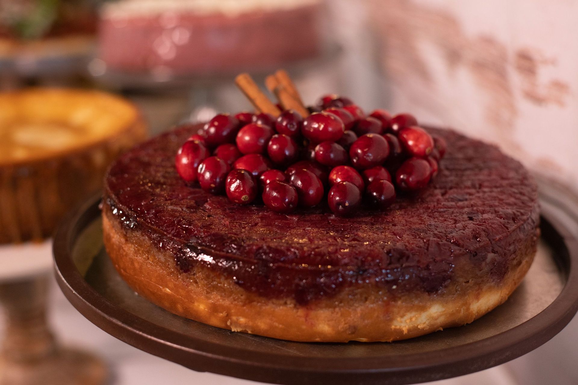 A cake with cranberries and cinnamon sticks on top