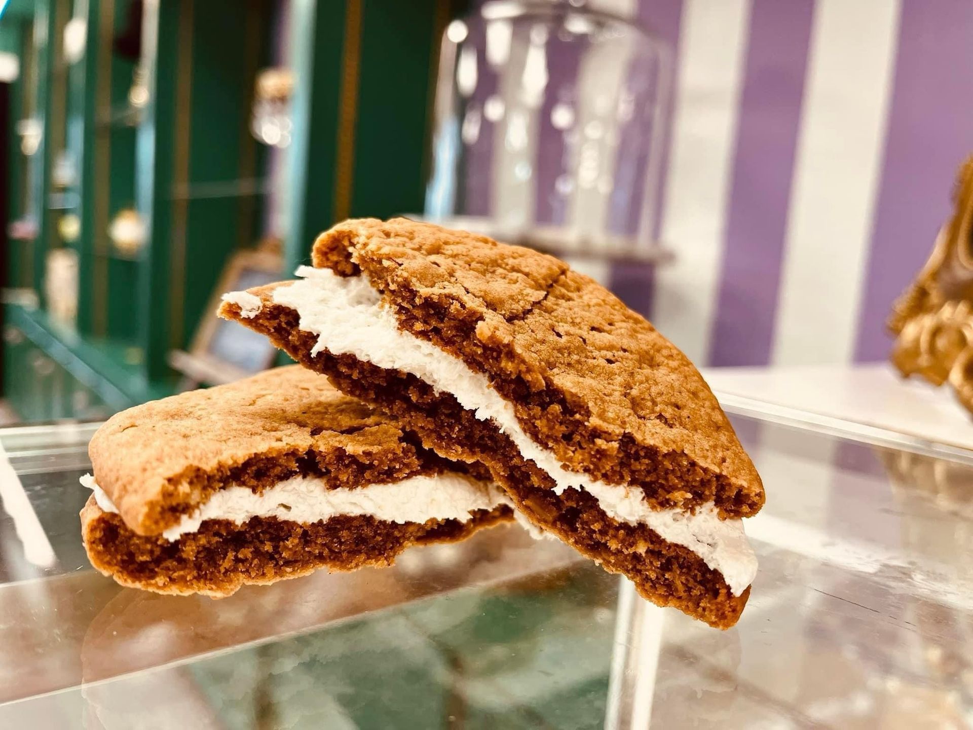 A cookie with whipped cream on it is sitting on a glass shelf.