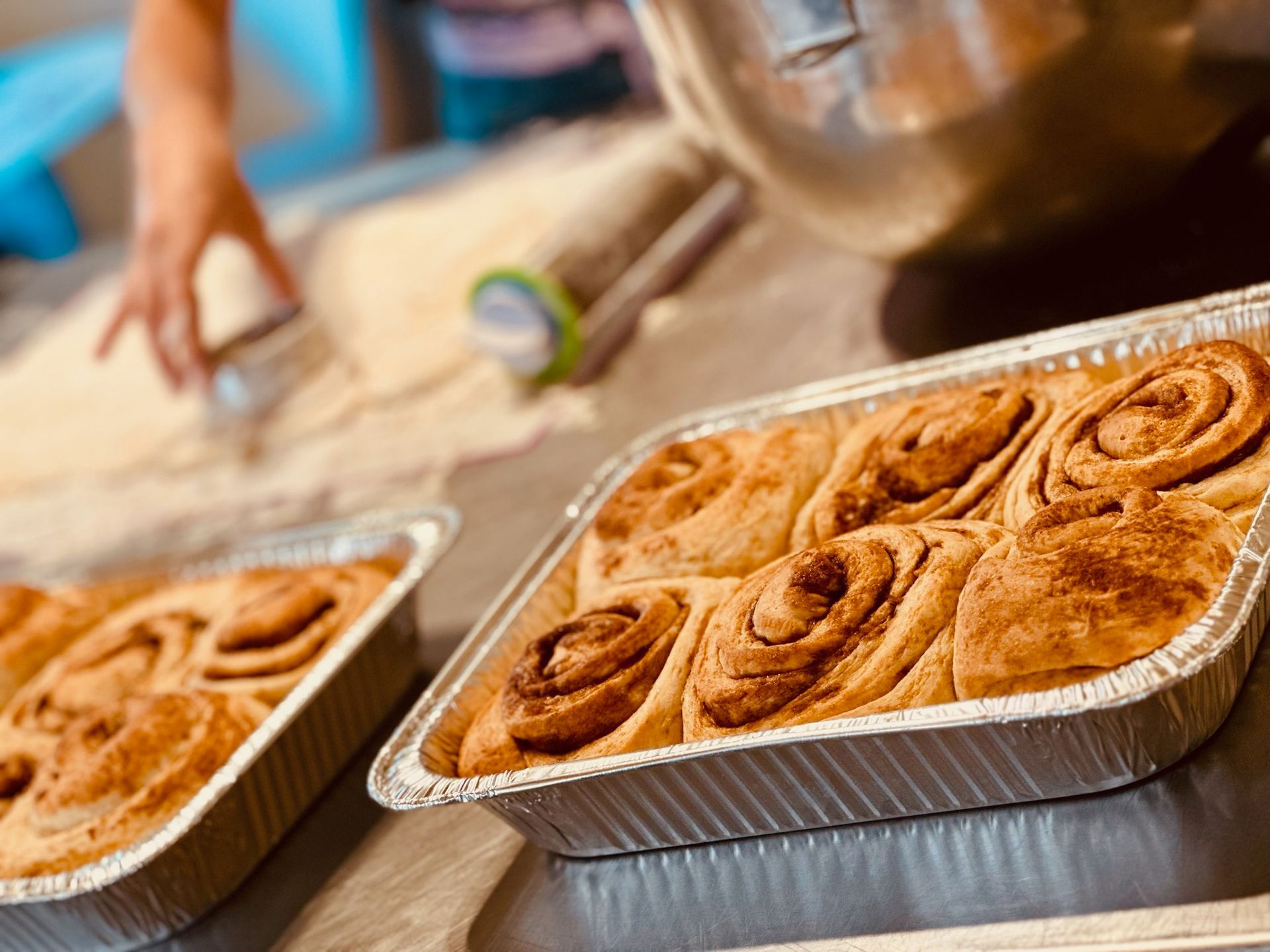 Two trays of cinnamon rolls are sitting on a table.