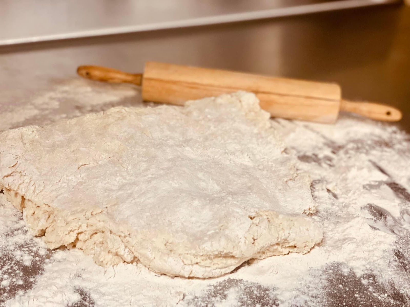 A piece of dough is sitting on a table next to a rolling pin.