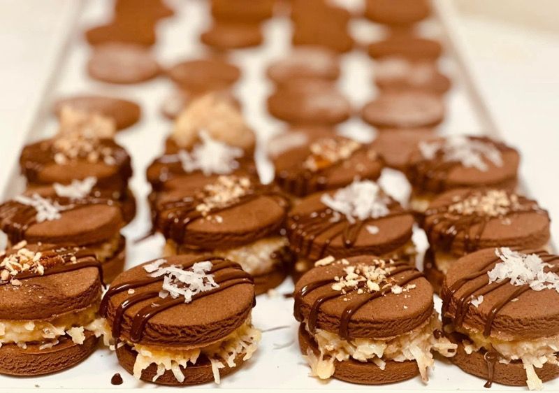 A tray of chocolate cookies with chocolate icing and coconut on top.