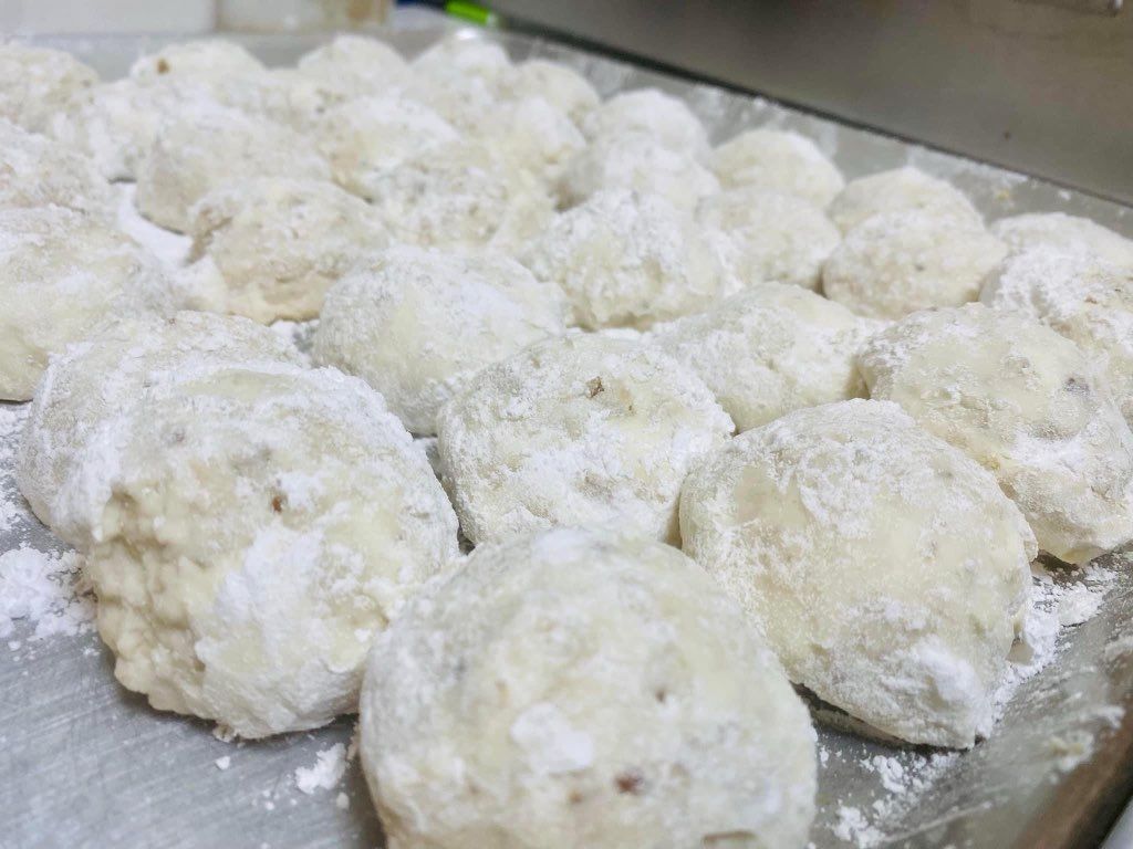 A bunch of cookies covered in powdered sugar on a table.