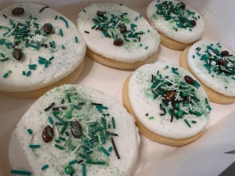 A box of cookies with white frosting and green sprinkles