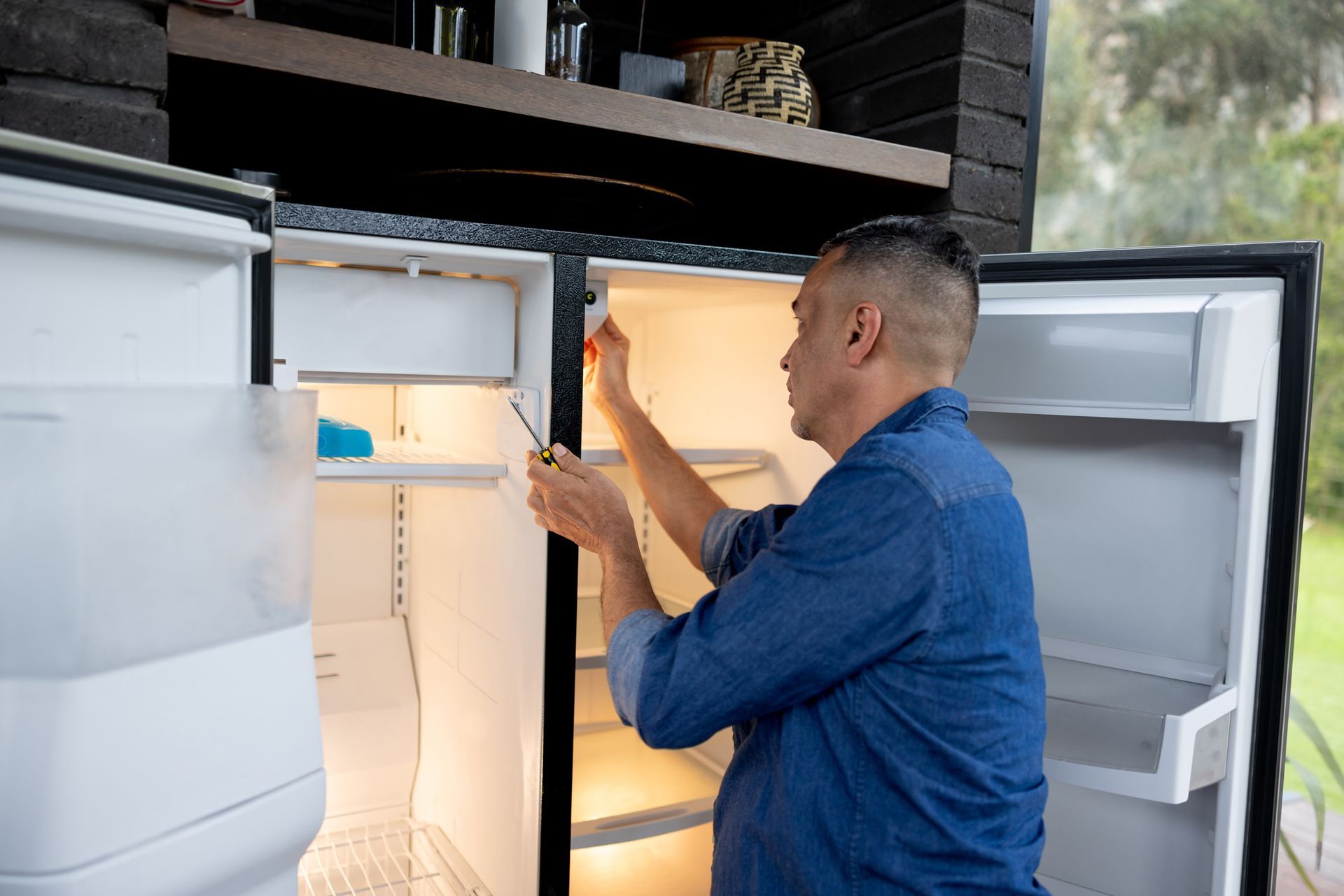 Technician fixing fridge inside residential house 