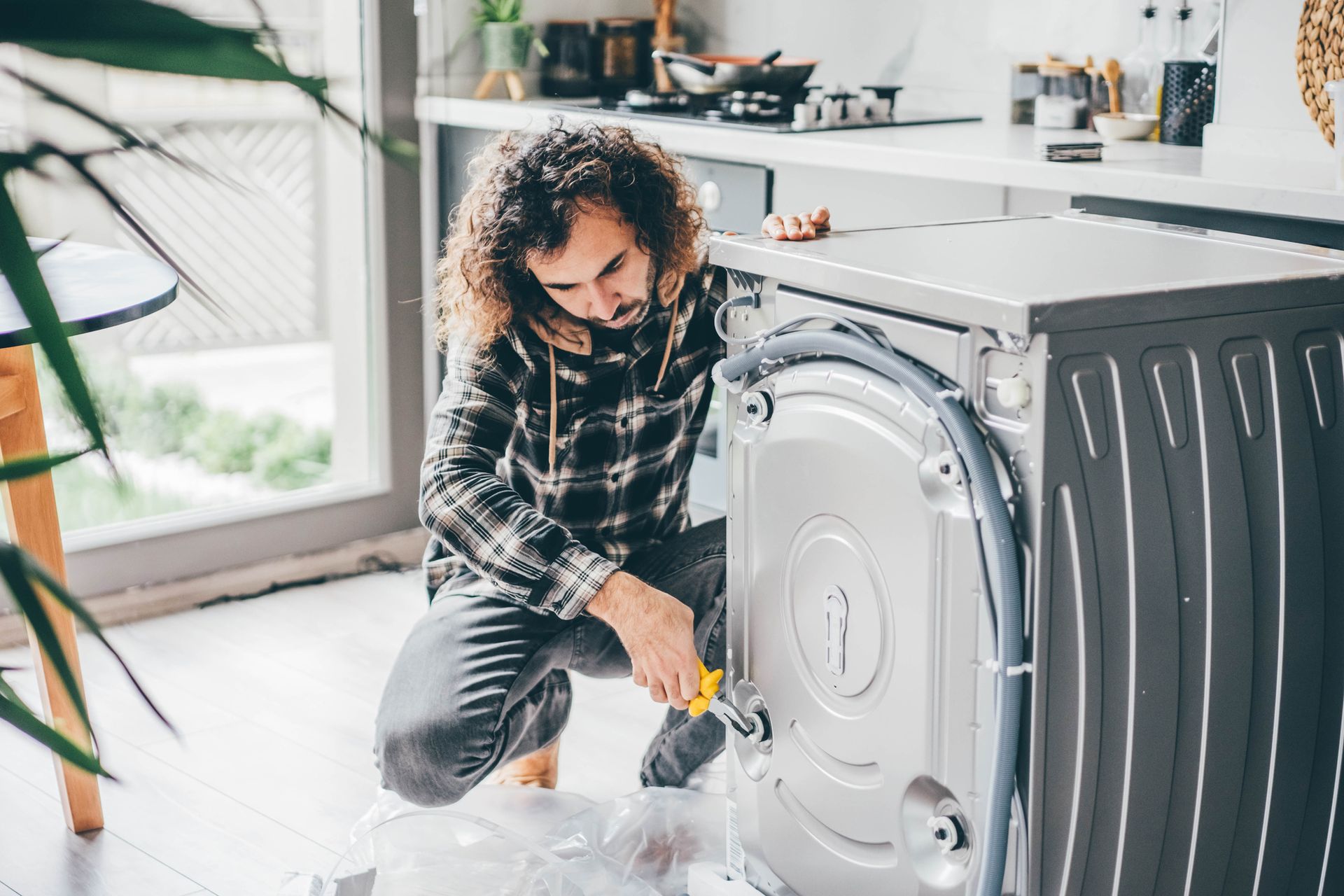 Person performing appliance repair on a washing machine.