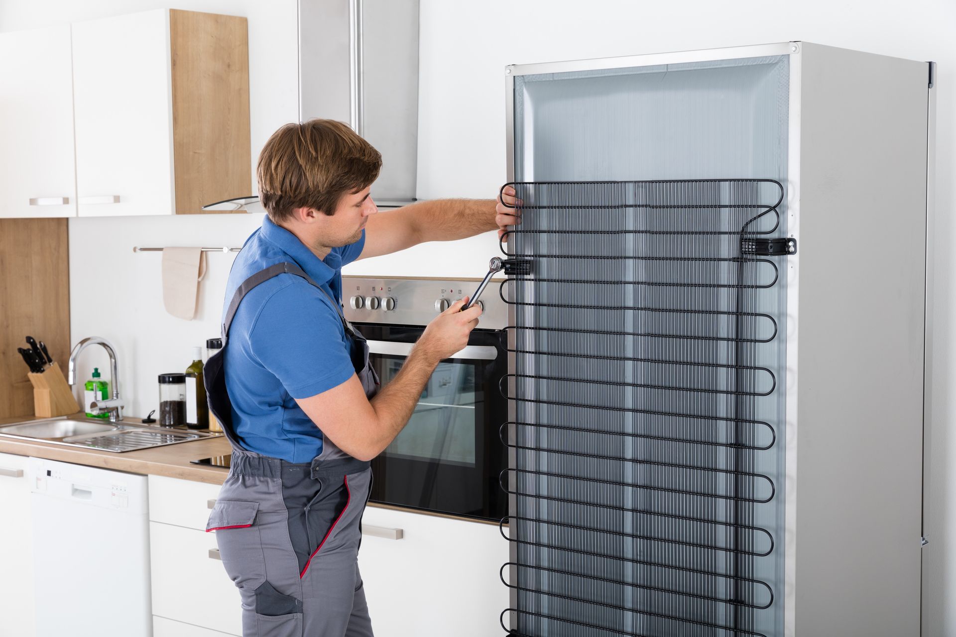 A contractor from Andy’s Appliance Repair is performing expert fridge repair at Frontenac, MO, using a screwdriver.