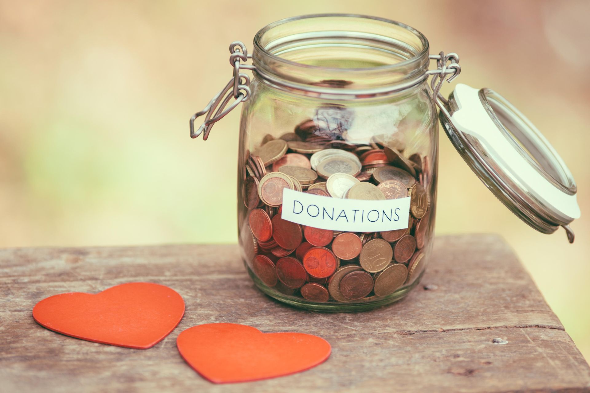 a jar filled with coins and two hearts on a wooden table .